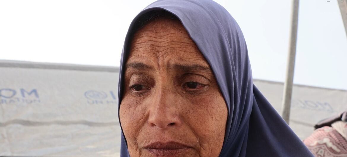صورة مقربة لسيدة فلسطينية ترتدي حجابا أزرق، تبدو حزينة أمام خيمة في غزة.