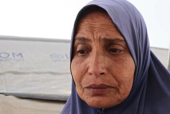 صورة مقربة لسيدة فلسطينية ترتدي حجابا أزرق، تبدو حزينة أمام خيمة في غزة.