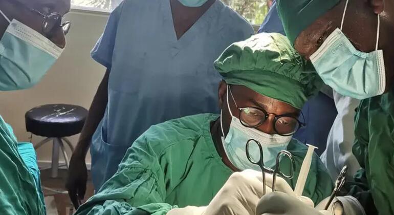 Madaktari wanaovaa mavazi ya kijani kibichi na vinyago hufanya upasuaji katika chumba cha upasuaji.