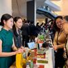 两位身着中国传统服饰和商务装的女性在一个展位上向两位参观者展示茶产品。