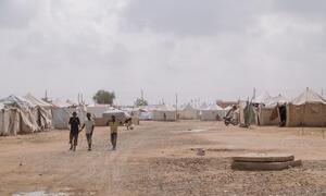 Children walk between rows of emergency tents at As-Senniya IDP site in Port Sudan, Sudan, where displaced families have sought refuge from violence. UNICEF provides integrated support including education, health, and nutrition services.