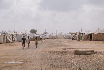 Children walk between rows of emergency tents at As-Senniya IDP site in Port Sudan, Sudan, where displaced families have sought refuge from violence. UNICEF provides integrated support including education, health, and nutrition services.