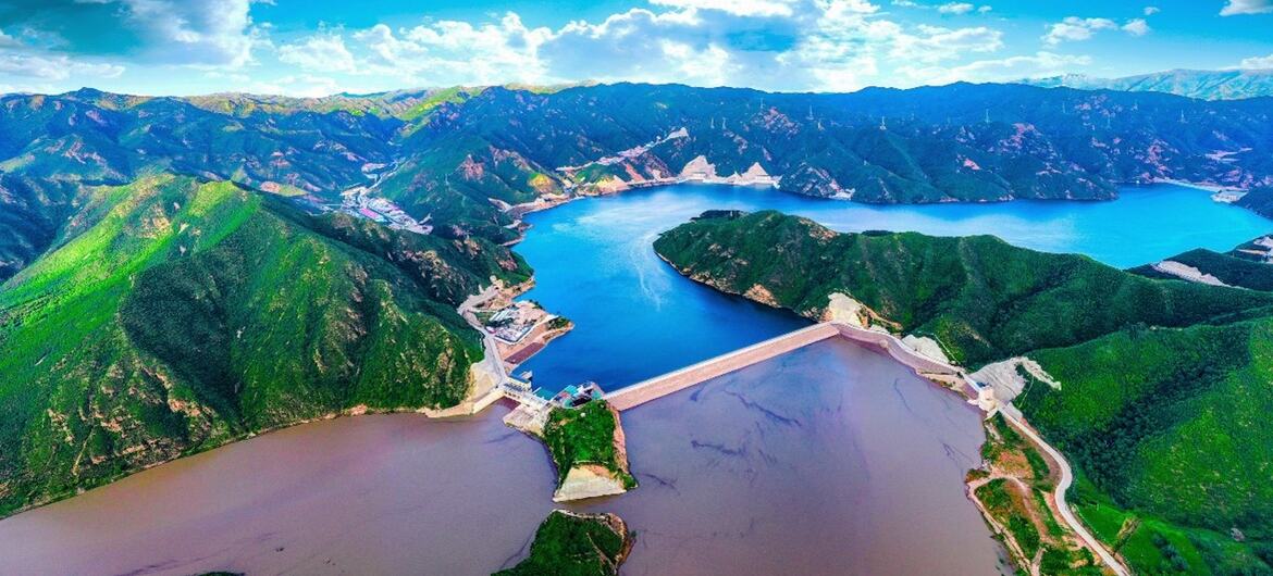 一个大水电的空中景象,位于绿色的山脉之间,