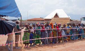 A line of displaced women in colorful attire waits for token verification to receive emergency food aid from WFP in Sange, Democratic Republic of Congo, on 19 December 2025.