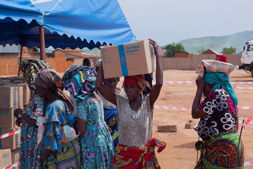 Mwanamke mmoja huko Sange, Wilaya ya Uvira, Jamhuri ya Kidemokrasia ya Kongo, anabeba sanduku la Biskuti za High Energy za WFP kichwani mwake baada ya kupokea msaada wa dharura wa chakula kwa familia za watu waliohamishwa.