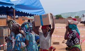 A woman in Sange, Uvira Territory, Democratic Republic of the Congo, carries a box of WFP's High Energy Biscuits on her head after receiving emergency food aid for displaced families.
