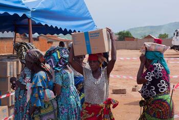 कांगो के लोकतांत्रिक गणराज्य के उवीरा क्षेत्र के संगे में एक महिला ने विस्थापित परिवारों के लिए आपातकालीन खाद्य सहायता प्राप्त करने के बाद अपने सिर पर डब्ल्यूएफपी के हाई एनर्जी बिस्किट का एक बॉक्स रखा है।