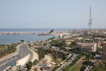 A panoramic view of Tripoli, Libya, showcasing the city's coastal layout, harbor, and surrounding urban areas from the rooftop of the Radisson Blu hotel.