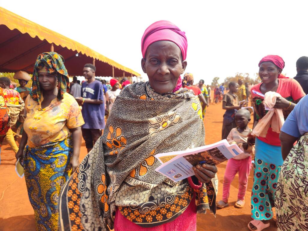 Mwanamke anayebeba hati katika kambi ya wakimbizi nchini Tanzania, akiwa amezungukwa na wakimbizi wengine, akikazia hali ya wakimbizi wa Burundi na juhudi za kurudisha nchini kwa hiari.