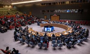 A wide view of the UN Security Council meeting on the situation in the Middle East, including the Palestinian question, with a speaker on a large screen.