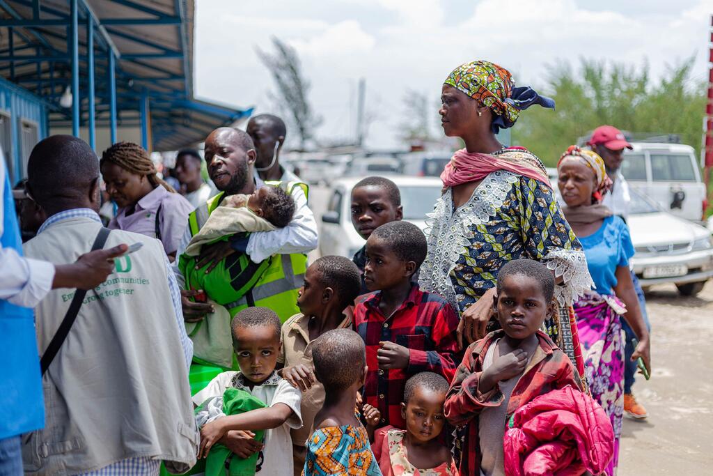 Un groupe de réfugiés africains, dont des femmes et des enfants, font la queue pour s'inscrire auprès d'un travailleur du HCR en RDC.