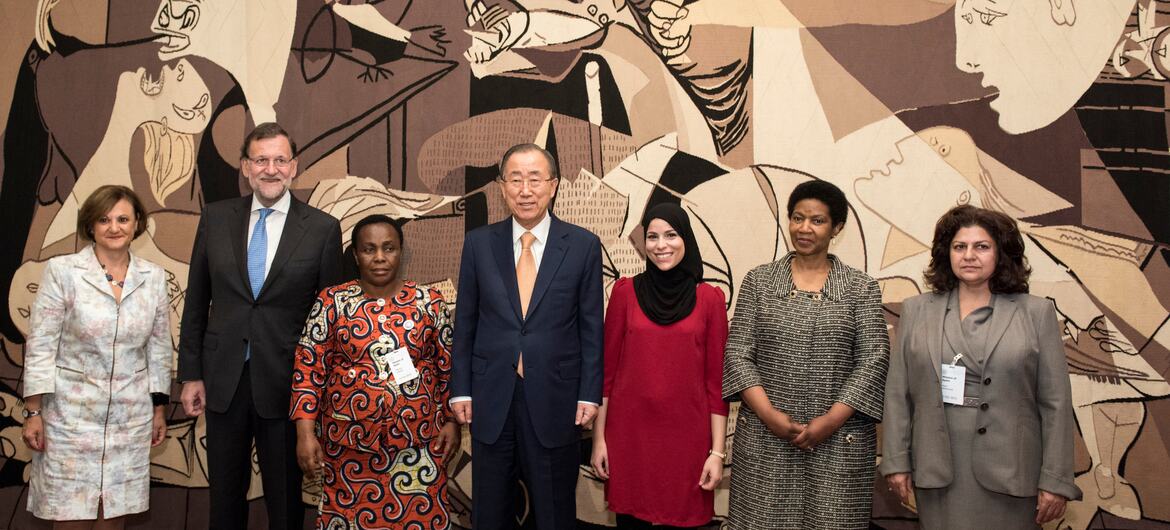 Um grupo de sete dignitários, incluindo funcionários da ONU e representantes de ONGs, posa para uma foto em frente a uma grande obra de arte. Da esquerda para a direita: Cristina Gallach, Mariano Rajoy, Julienne Lusenge, Ban Ki-moon, Alaa Murabit, Phumzile Mlambo-Ngcuka e Yanar Mohammed.