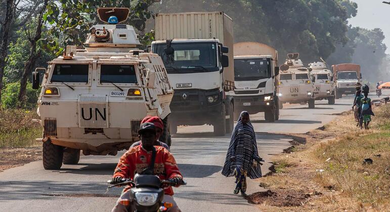 Конвой бронетранспортных средств и грузовиков миротворцев ООН перевозит избирательные материалы в Сибуте, Центральноафриканская Республика, с местными жителями вблизи.