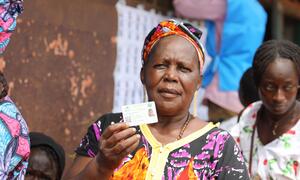 A woman in Central African Republic holds up her voter ID card at a polling station during the 2025-2026 elections.