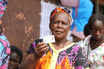 A woman in Central African Republic holds up her voter ID card at a polling station during the 2025-2026 elections.