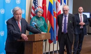 UN Secretary-General António Guterres speaking at a podium during a Security Council media stakeout about the situation in the Middle East, with other officials standing behind him.