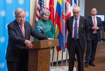 UN Secretary-General António Guterres speaking at a podium during a Security Council media stakeout about the situation in the Middle East, with other officials standing behind him.