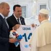 L'ancien footballeur international français Mikaël Silvestre et l'entrepreneur Paolo Celi présentent un maillot de football blanc avec le nom 'LEONE' et le numéro 14 au pape Léon XIV au Vatican, aux côtés d'un ballon de football. Cette réunion promeut l'initiative des Nations Unies Football for the Goals.