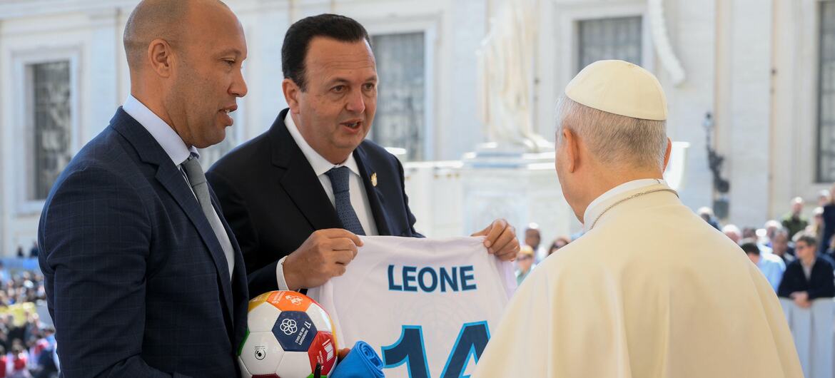 L'ancien footballeur international français Mikaël Silvestre et l'entrepreneur Paolo Celi présentent un maillot de football blanc avec le nom 'LEONE' et le numéro 14 au pape Léon XIV au Vatican, aux côtés d'un ballon de football. Cette réunion promeut l'initiative des Nations Unies Football for the Goals.