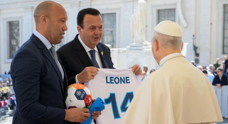 L'ancien footballeur international français Mikaël Silvestre et l'entrepreneur Paolo Celi présentent un maillot de football blanc avec le nom 'LEONE' et le numéro 14 au pape Léon XIV au Vatican, aux côtés d'un ballon de football. Cette réunion promeut l'initiative des Nations Unies Football for the Goals.
