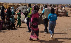 A UNICEF worker walks through an IDP camp in Tawila, North Darfur, Sudan, surrounded by displaced families and makeshift shelters.