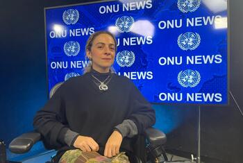 Constança Entrudo, uma mulher com cabelos castanhos claros, está sentada em frente a uma tela azul que exibe 'ONU NEWS' e o logotipo das Nações Unidas.