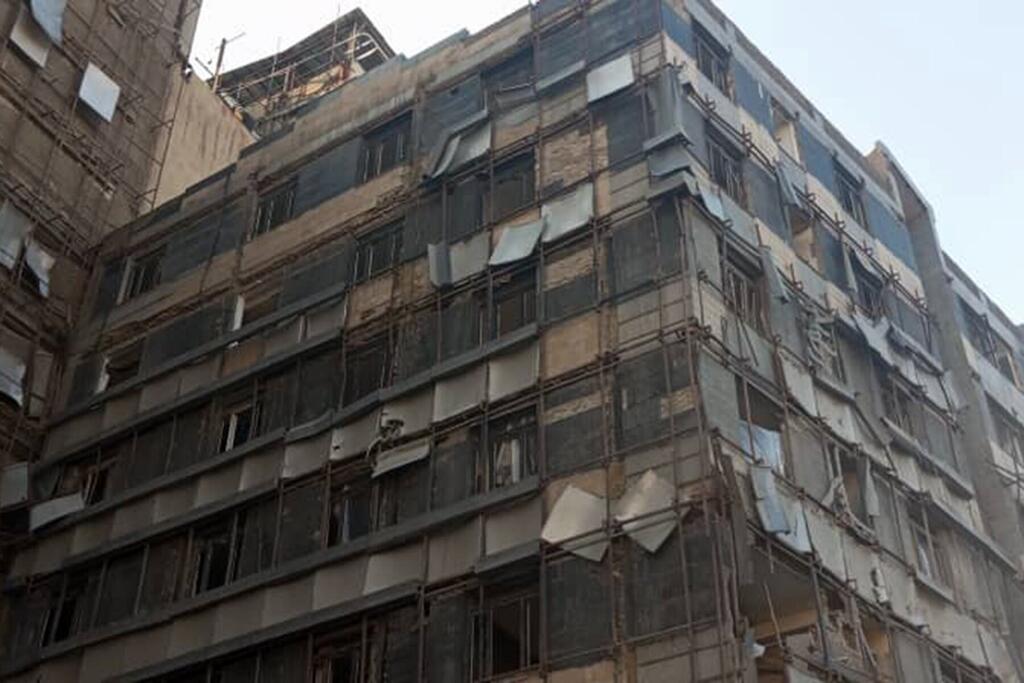Un edificio de hormigón de varios pisos en Irán con una fachada revestida, con numerosas ventanas y algunos andamios.