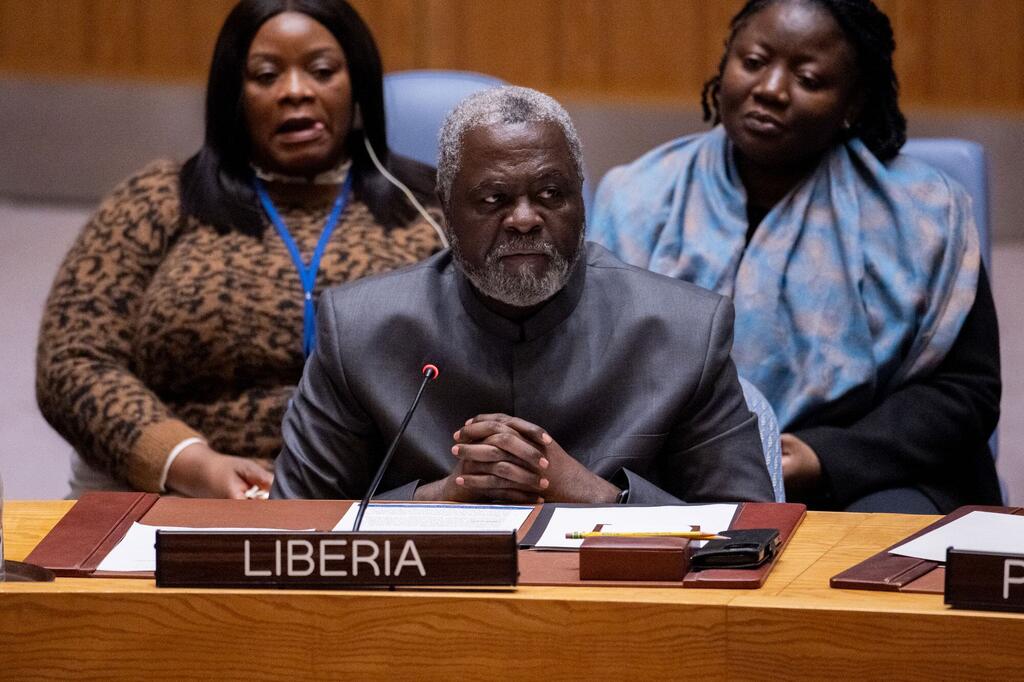 Mwanamume anayewakilisha Liberia ameketi kwenye meza ya mkutano akiwa na bamba la jina, akiwa amezungukwa na wanawake wawili, wakati wa mkutano wa Baraza la Usalama la Umoja wa Mataifa kuhusu hali katika Jamhuri ya Kidemokrasia ya Kongo.