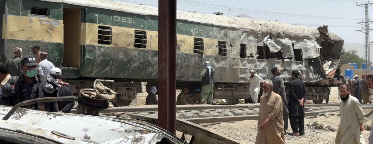 Voiture de train endommagée sur les rails à Quetta, au Pakistan, après une attaque par voiture piégée. Des hommes et des policiers sont sur place.
