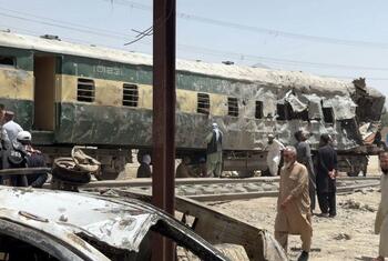 Voiture de train endommagée sur les rails à Quetta, au Pakistan, après une attaque par voiture piégée. Des hommes et des policiers sont sur place.