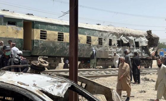 کوئٹہ، پاکستان میں ریلوے ٹریک پر ایک ٹرین کی گاڑی کو کار بم حملے کے بعد نقصان پہنچا۔ مرد اور پولیس اہلکار موقع پر موجود ہیں۔