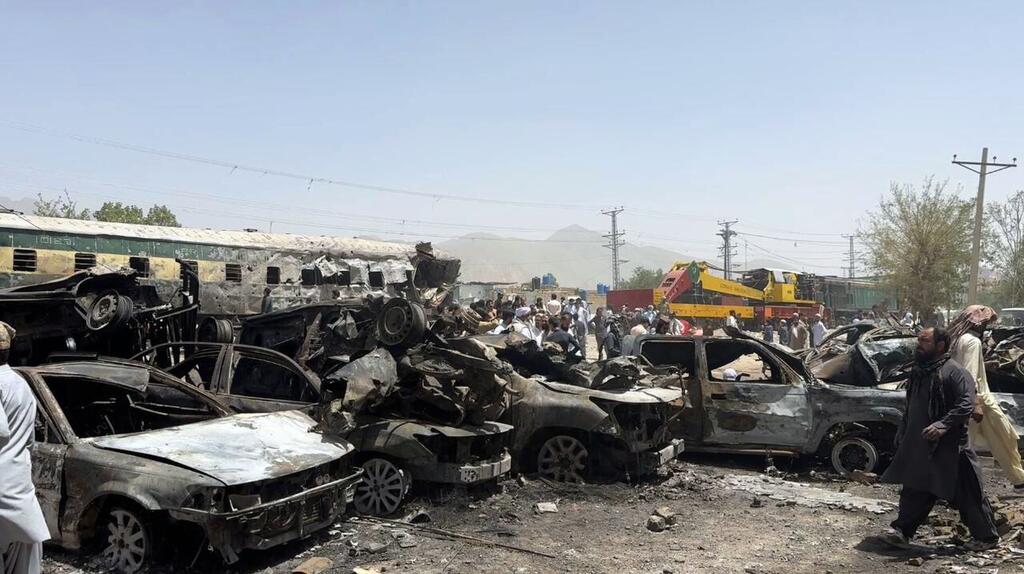 Débris d'une attaque par train et voiture à Quetta, au Pakistan, avec des véhicules endommagés et une foule de personnes sur les lieux.