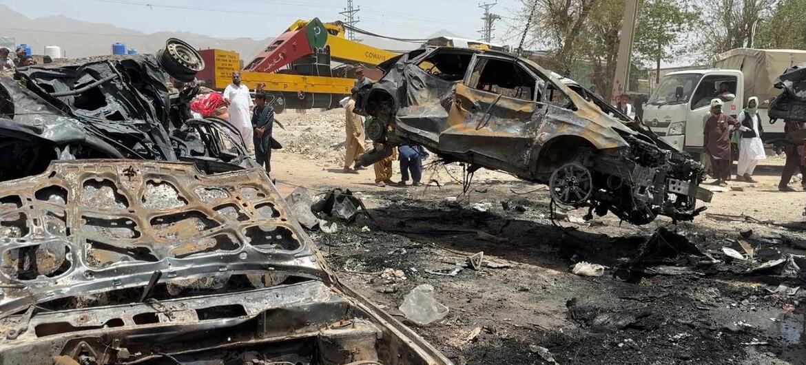 کوئٹہ، پاکستان میں ٹرین حملے کے مقام پر جلنے والی گاڑی کے ملبے، ایمرجنسی عملے اور ناظرین کے ساتھ۔