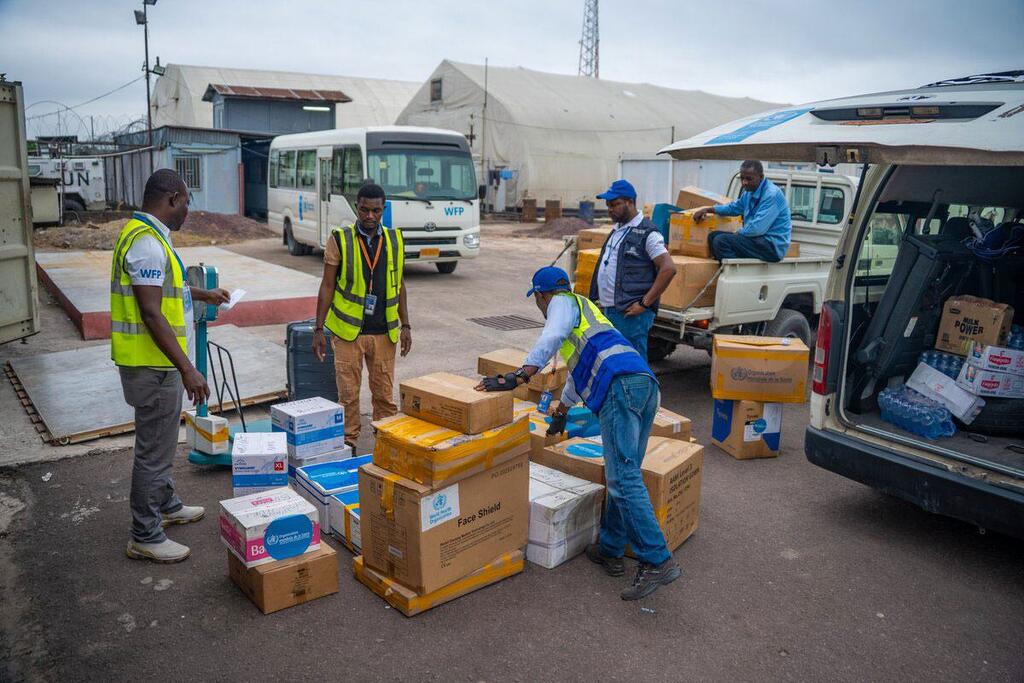 Wafanyakazi wa WFP na watawala wanabeba masanduku ya vifaa, ikiwemo kinga za uso, kwenye kituo cha usafirishaji katika Jamhuri ya Kidemokrasia ya Kongo wakati wa mlipuko wa Ebola.