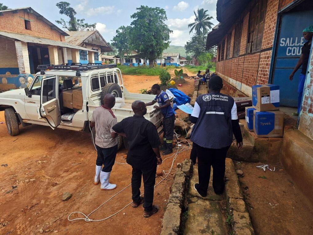 Des travailleurs de l'OMS déchargent des fournitures d'un véhicule dans une clinique en RDC.