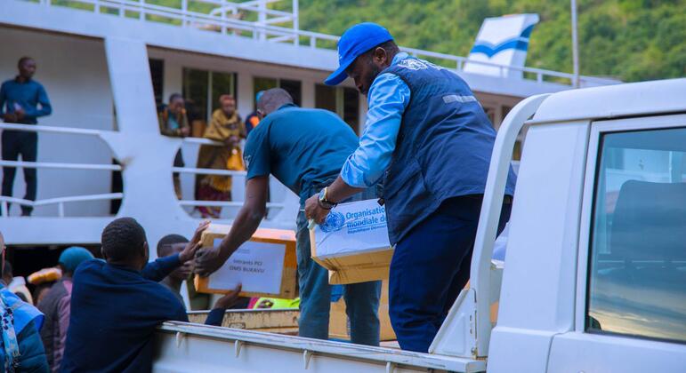 Wafanyakazi wa Shirika la Afya la Umoja wa Mataifa (WHO) wanapakua vifaa vya matibabu kutoka kwenye lori nyeupe hadi kwenye mashua katika Jamhuri ya Kidemokrasia ya Kongo.