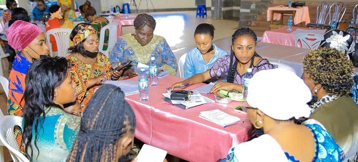 Mujeres reunidas alrededor de una mesa de registro en un taller de la MONUSCO en Lubero, Kivu del Norte, RDC.
