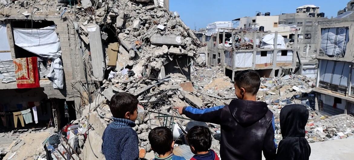Des enfants se tiennent sur le toit d'une maison détruite et observent les décombres à Gaza-Ville.