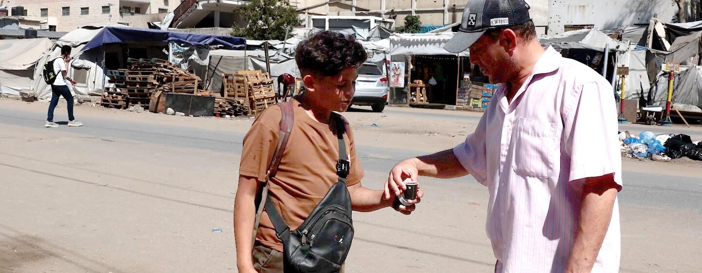 Un jeune garçon palestinien vend du café à un homme dans une rue de Gaza pendant l'Aïd.
