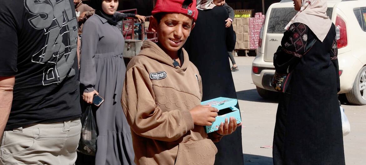 Un garçon palestinien vend du chocolat dans une petite boîte à un marché de Gaza pendant l'Aïd.