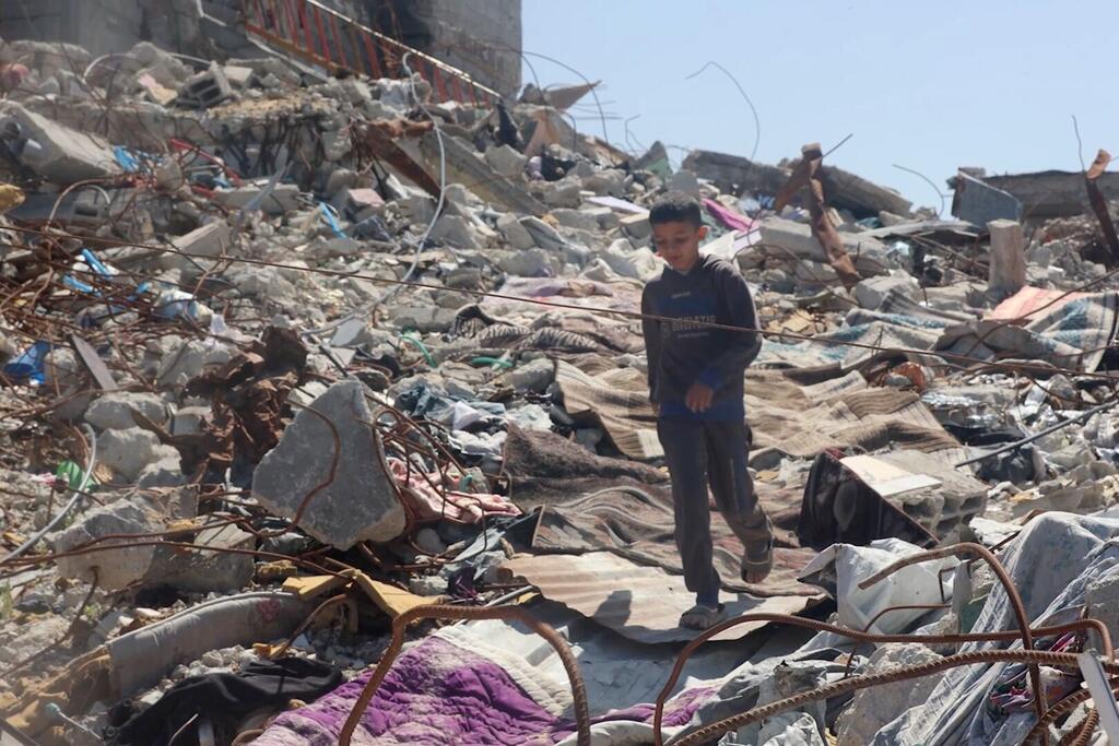 A young Palestinian boy walks through the rubble and debris of a destroyed building in Gaza.