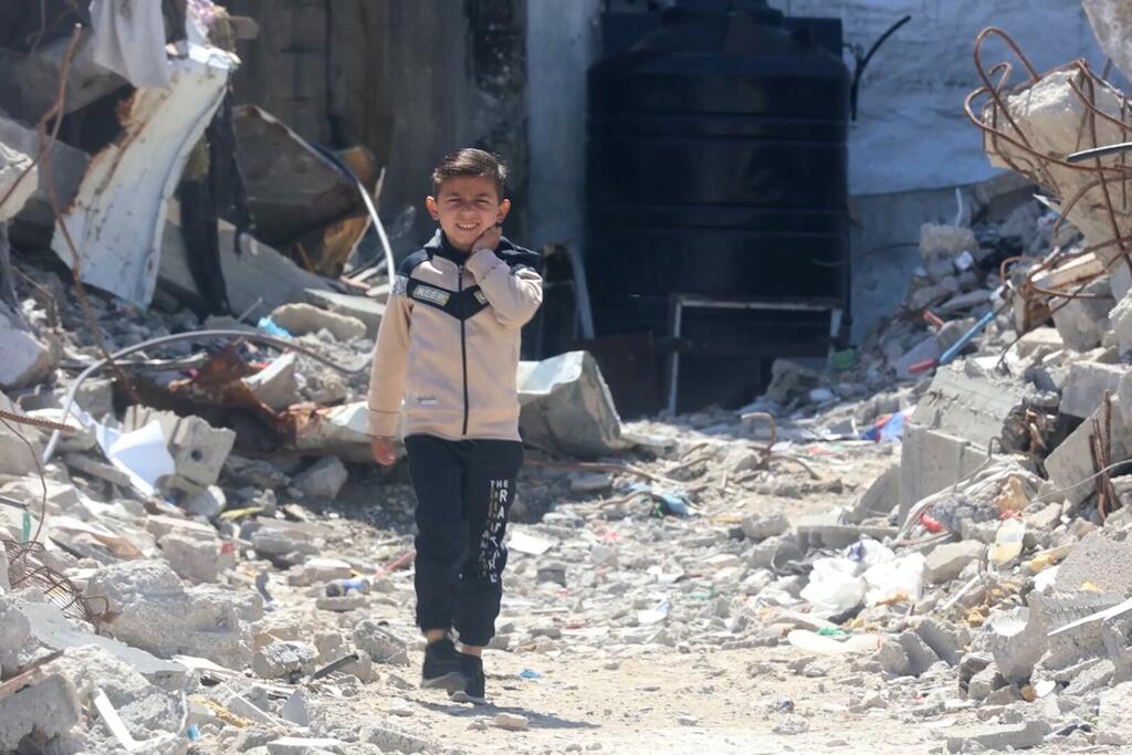 Un jeune garçon marche et sourit au milieu des décombres dans la ville de Gaza.