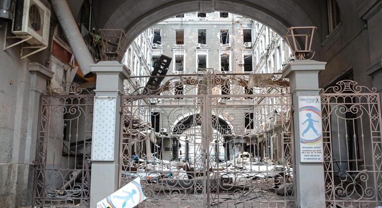 Damaged buildings and a broken gate are visible in a war-torn street in Kharkov, Ukraine.