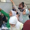 Los niños levantan las manos para responder preguntas en un centro de aprendizaje apoyado por UNICEF en la Escuela Aeshyia en Deir al-Balah, Gaza, estudiando bajo tiendas de campaña en medio de infraestructuras dañadas.
