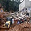 Soldados do Departamento de Bombeiros e voluntários conduzem uma operação de resgate em meio aos escombros de casas enterradas sob lama após fortes chuvas em Juiz de Fora, Brasil.