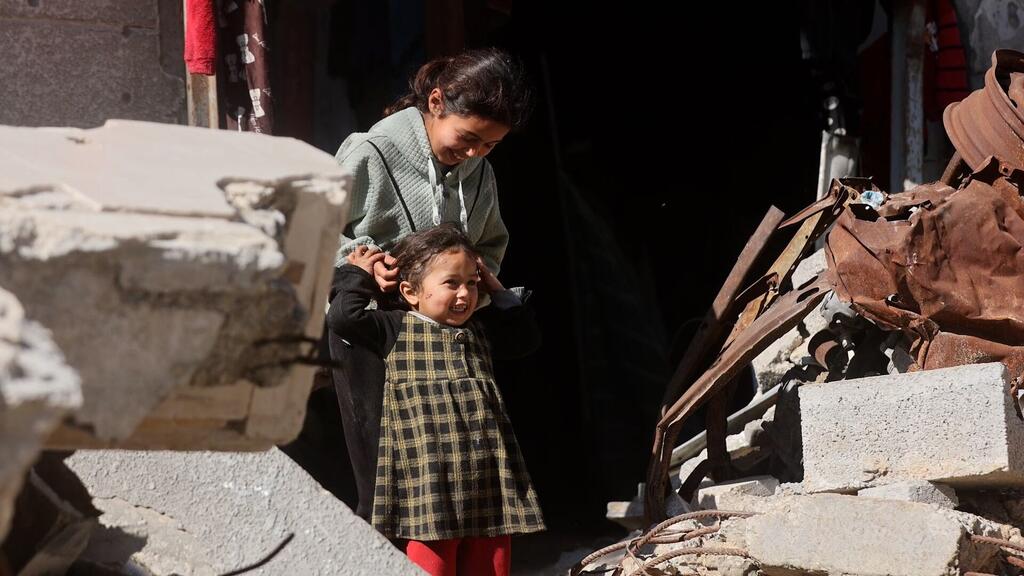 Deux jeunes filles palestiniennes se tiennent au milieu des décombres de béton et des débris métalliques tordus dans la ville de Gaza, souriantes tout en jouant au soleil.