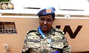 Mwanamke ambaye ni fundi wa mitambo wa jeshi la Ethiopia, Tigist Felede, akivaa sare ya kijeshi akiwa na beret ya wanajeshi wa kulinda amani wa Umoja wa Mataifa, akiwa amesimama mbele ya gari la kijeshi.