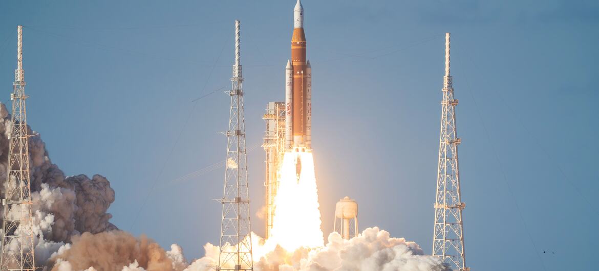 يُطلق صاروخ ناسا SLS مع مركبة أوريون الفضائية على قمته من مركز كينيدي للفضاء في فلوريدا، مُعلِنًا عن انطلاق مهمة أرتيميس الثانية. يرتفع الصاروخ الضخم في السماء، تاركًا وراءه أثرًا من العادم الساطع ودخانًا كثيفًا.