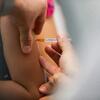 Uma imagem em close-up de um profissional de saúde administrando uma injeção da vacina contra o HPV no braço de uma criança no Brasil.