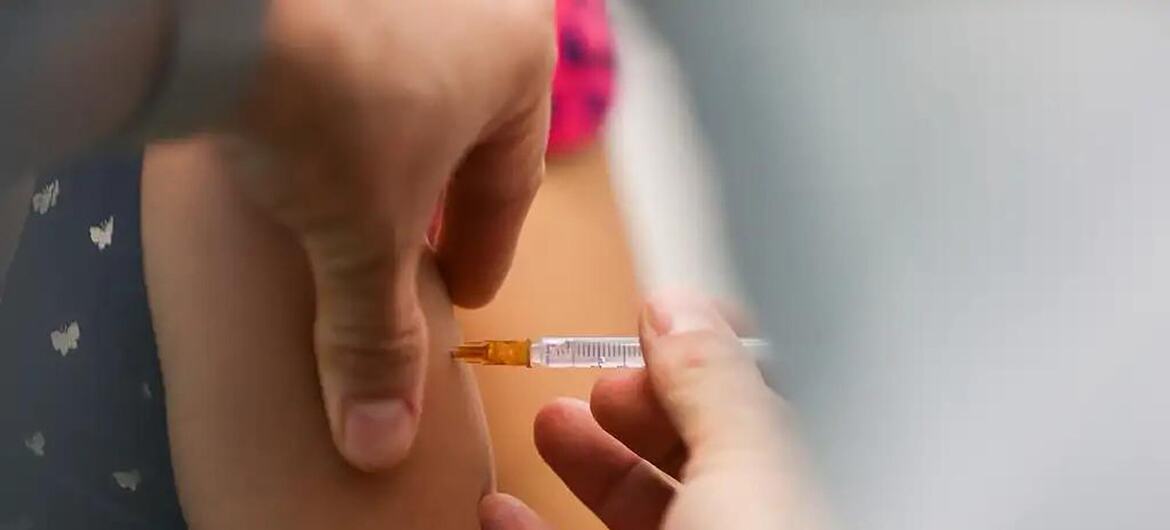 Una toma de primer plano de un trabajador de la salud administrando una inyección de la vacuna contra el VPH en el brazo de un niño en Brasil.
